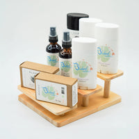 Natural skincare products display featuring Bluebird Naturals deodorant, bug spray, and handmade soap, and Blakbird organic soap on a wooden stand, eco-friendly personal care items for sensitive skin.